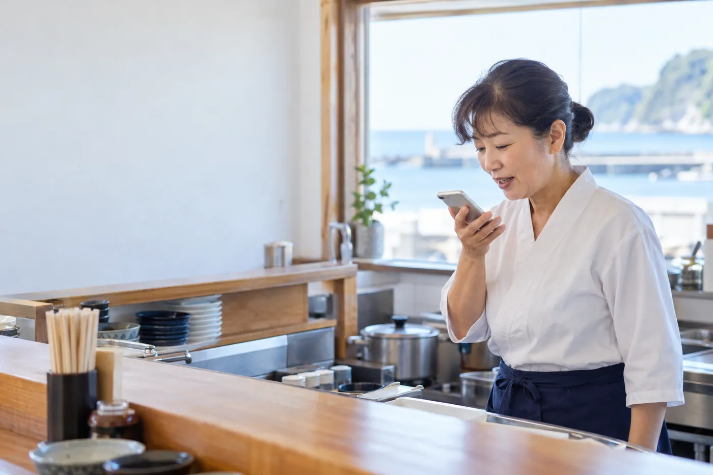 食堂でスマホに話しかける店主